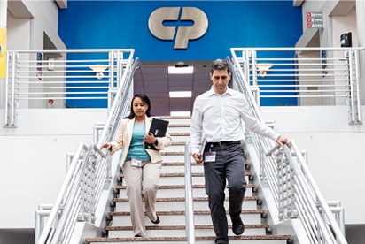 Medewerkers van Colgate-Palmolive lopen een trap af, met achter hen het Colgate-Palmolive-logo op een blauwe muur.